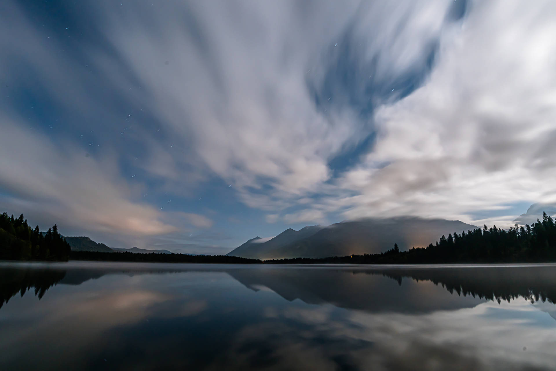 A Peaceful Lake Surrounded By A Dim Cloudy Sky.