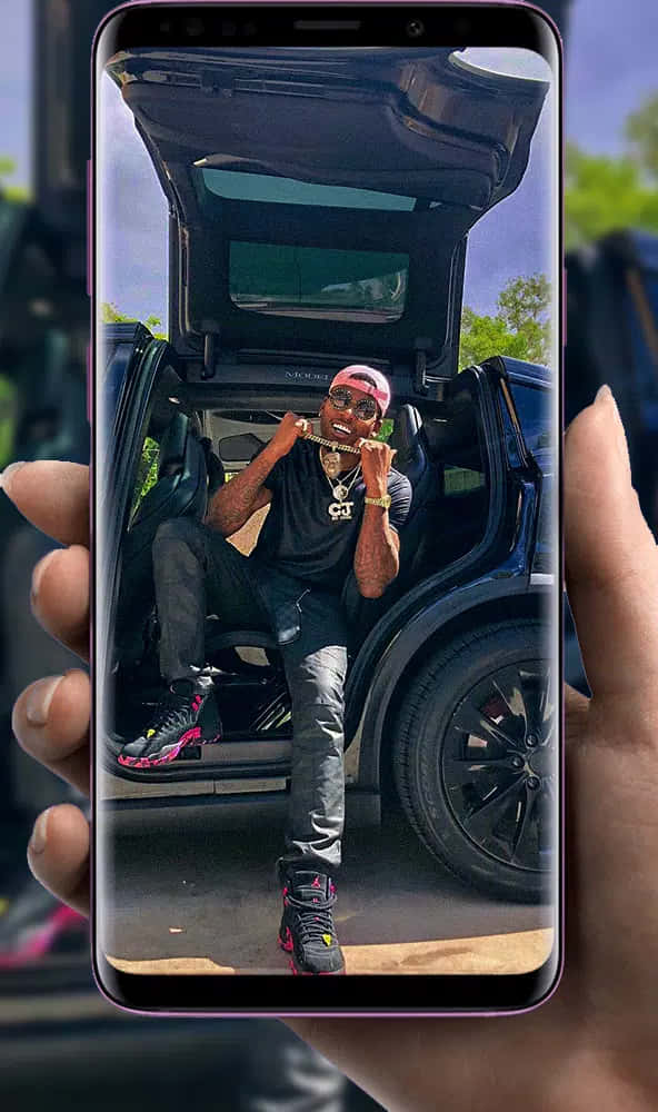 A Person Holding A Phone With A Picture Of A Car Background