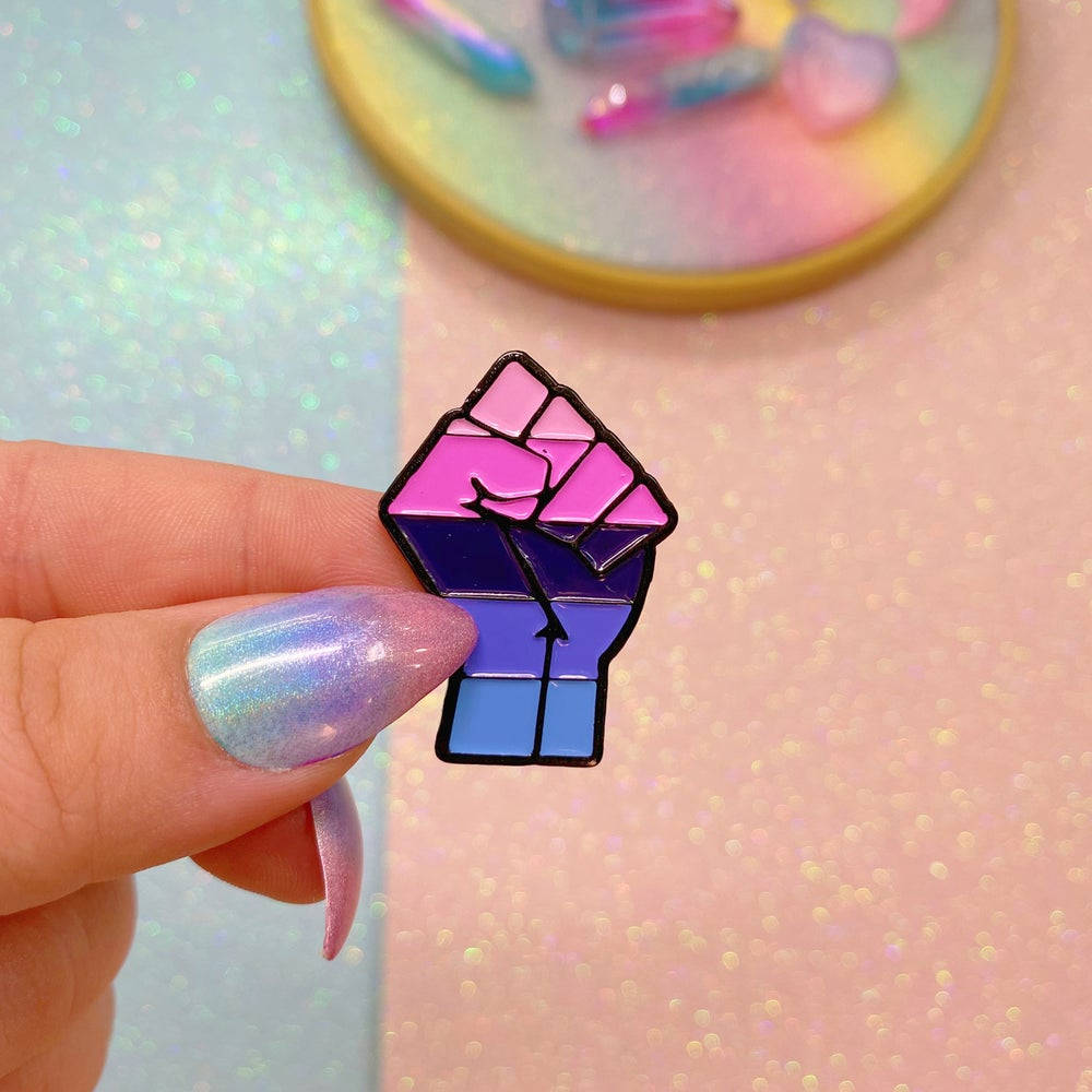 A Person Holding A Pin With A Rainbow Fist Background