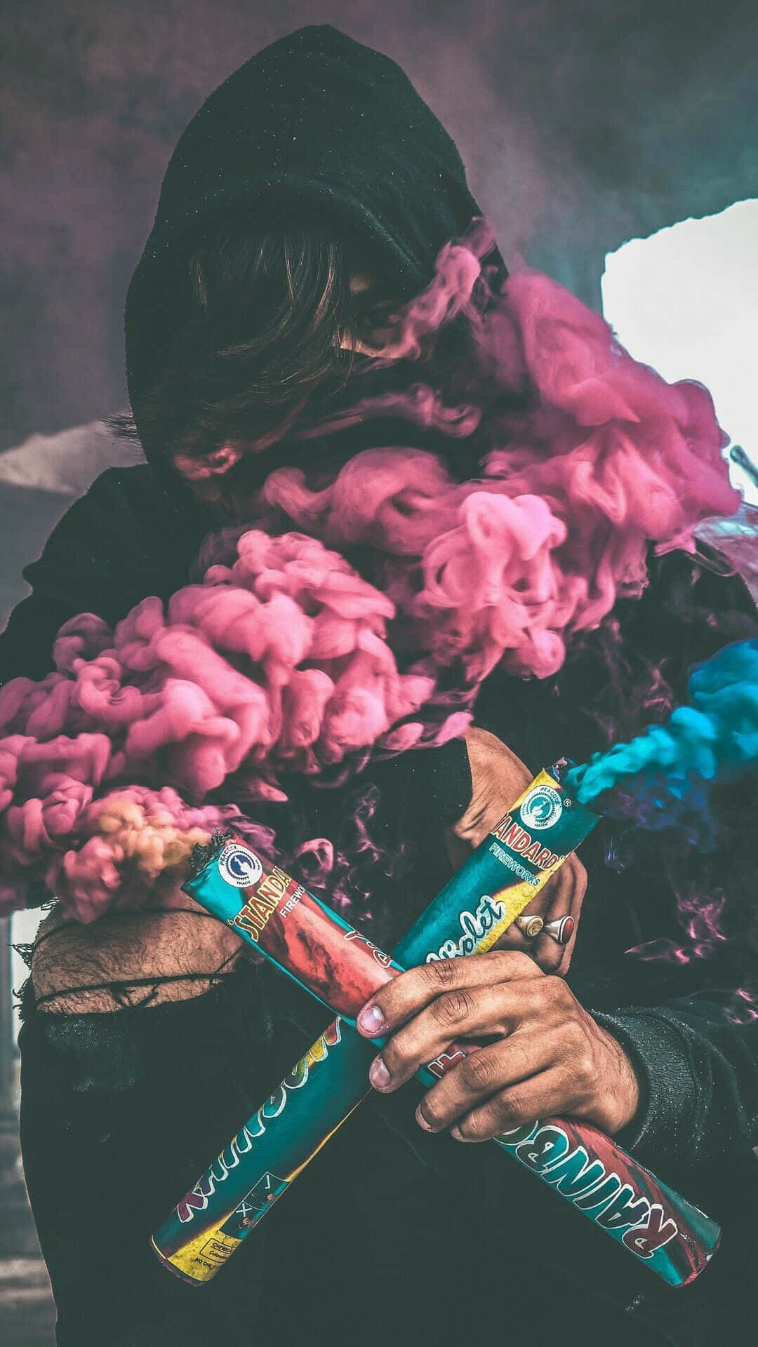 A Person Holding A Pink And Blue Smoke Background
