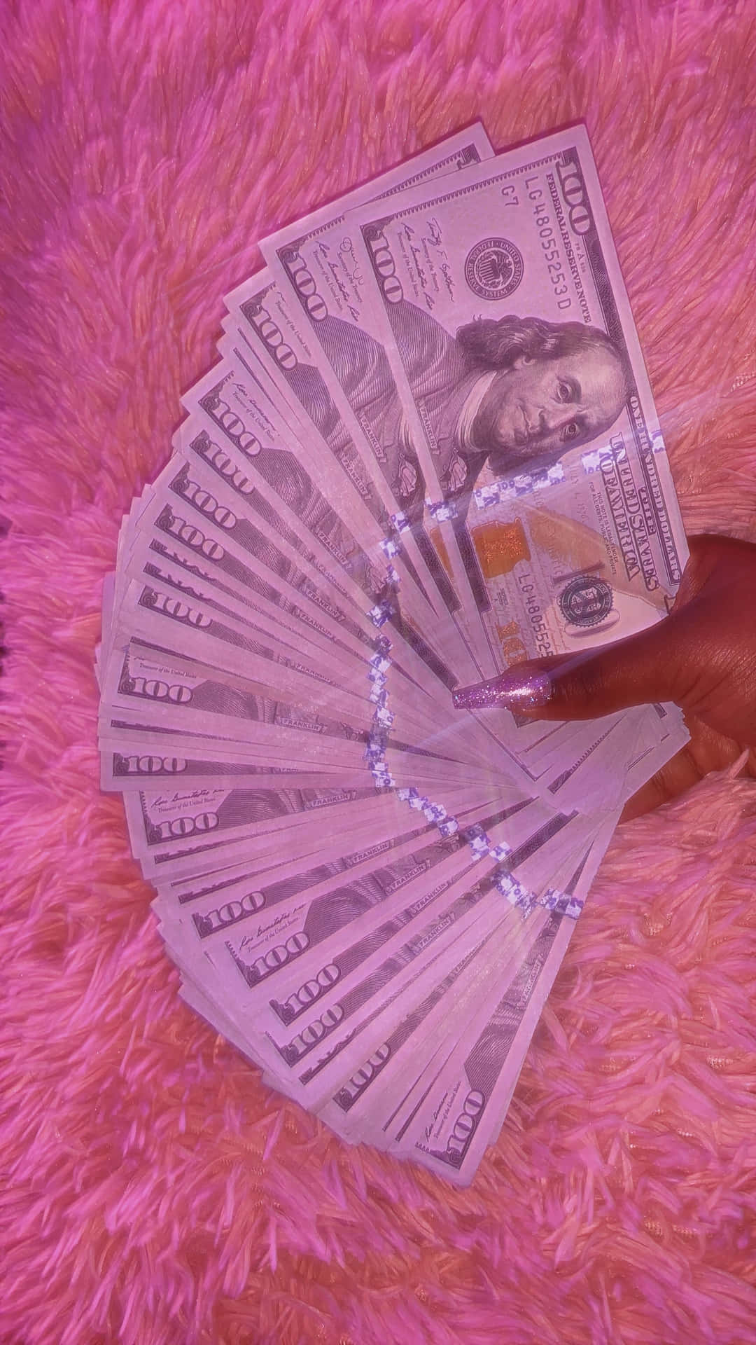 A Person Holding A Pink Dollar Bill On A Pink Blanket