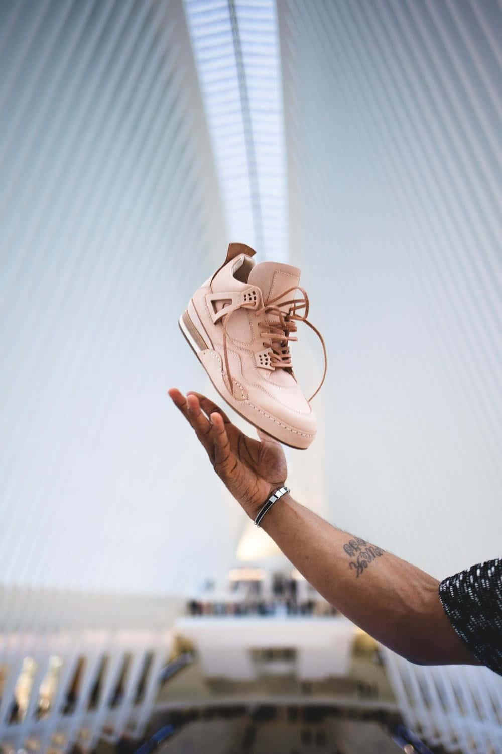 A Person Holding A Pink Shoe In Front Of A Building Background