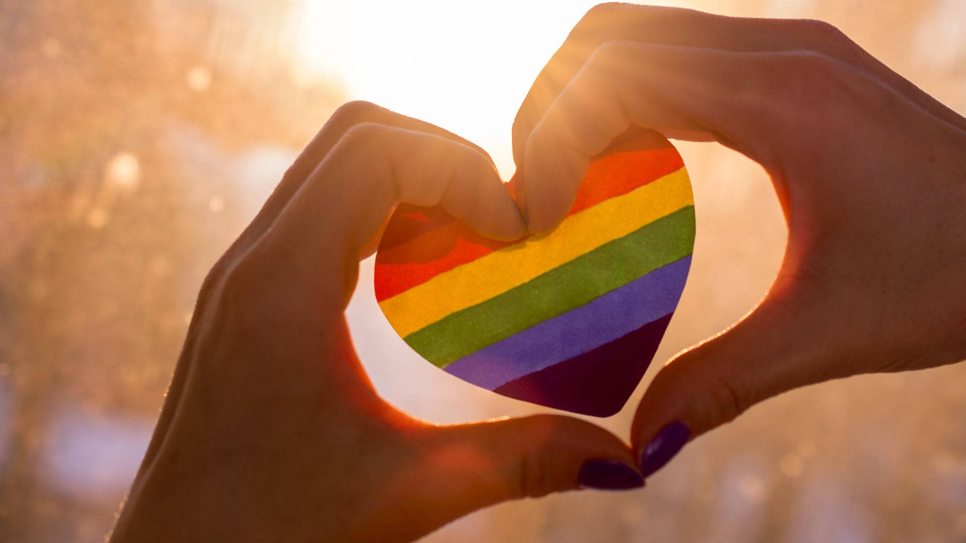 A Person Holding A Rainbow Heart In Their Hands Background