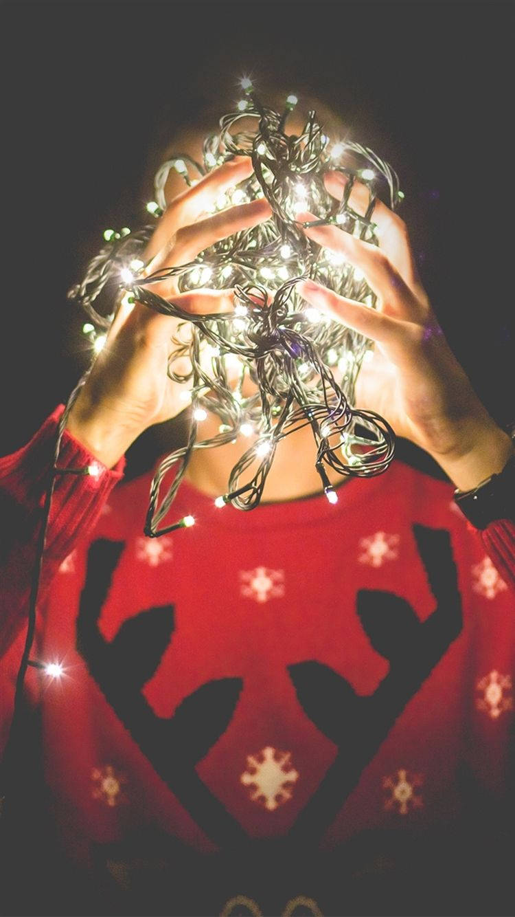 A Person Holding Up A Christmas Light Background