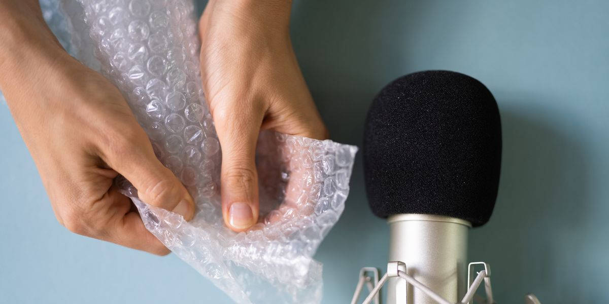 A Person Is Holding A Microphone And Wrapping A Piece Of Bubble Wrap Background