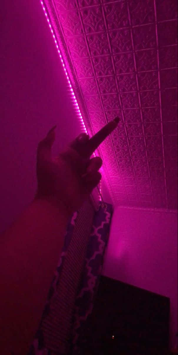 A Person Is Holding Up A Pink Led Light Background