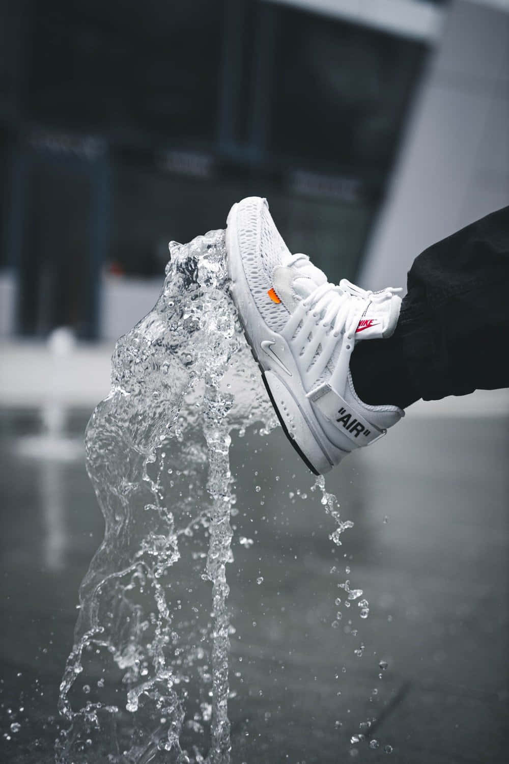 A Person Is Standing In Front Of A Fountain With A Pair Of Sneakers Background
