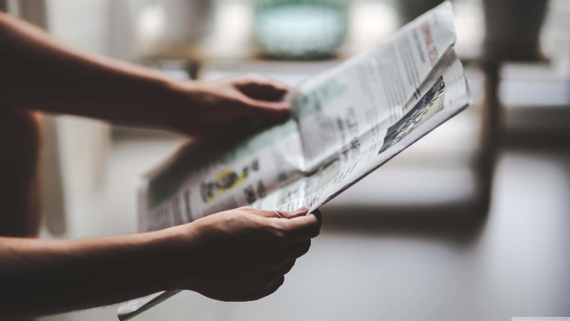 A Person Reading A Newspaper In Front Of A Window Background