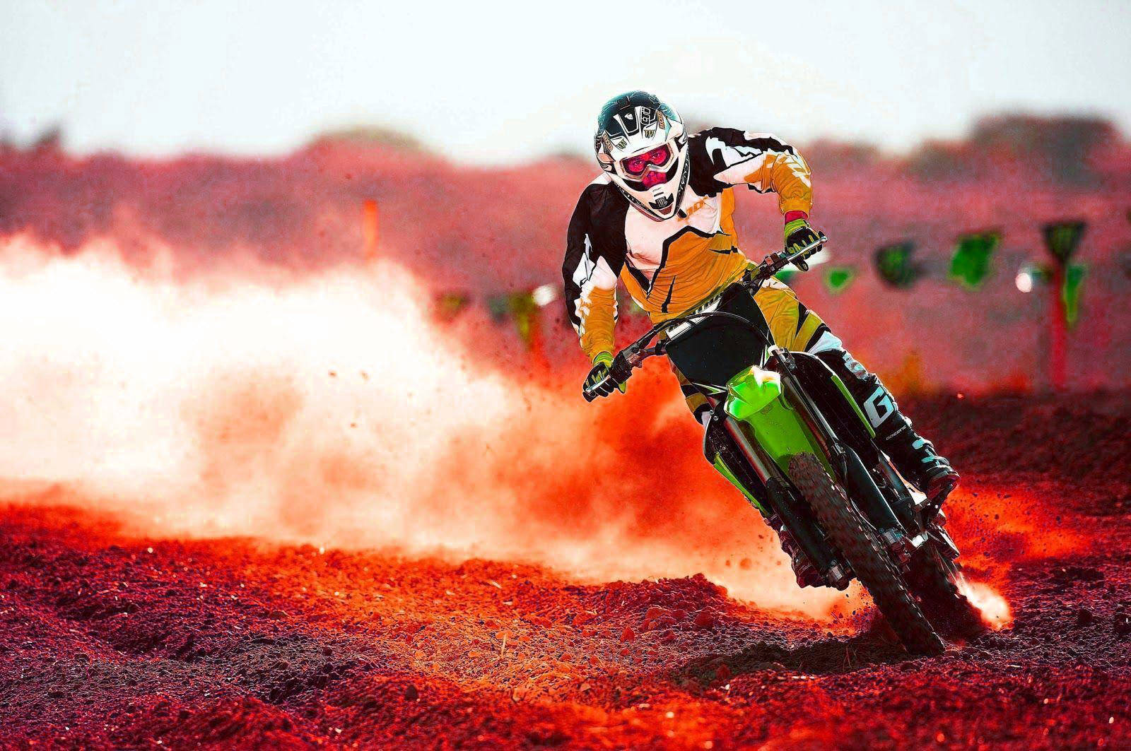 A Person Riding A Dirt Bike On A Red Field Background