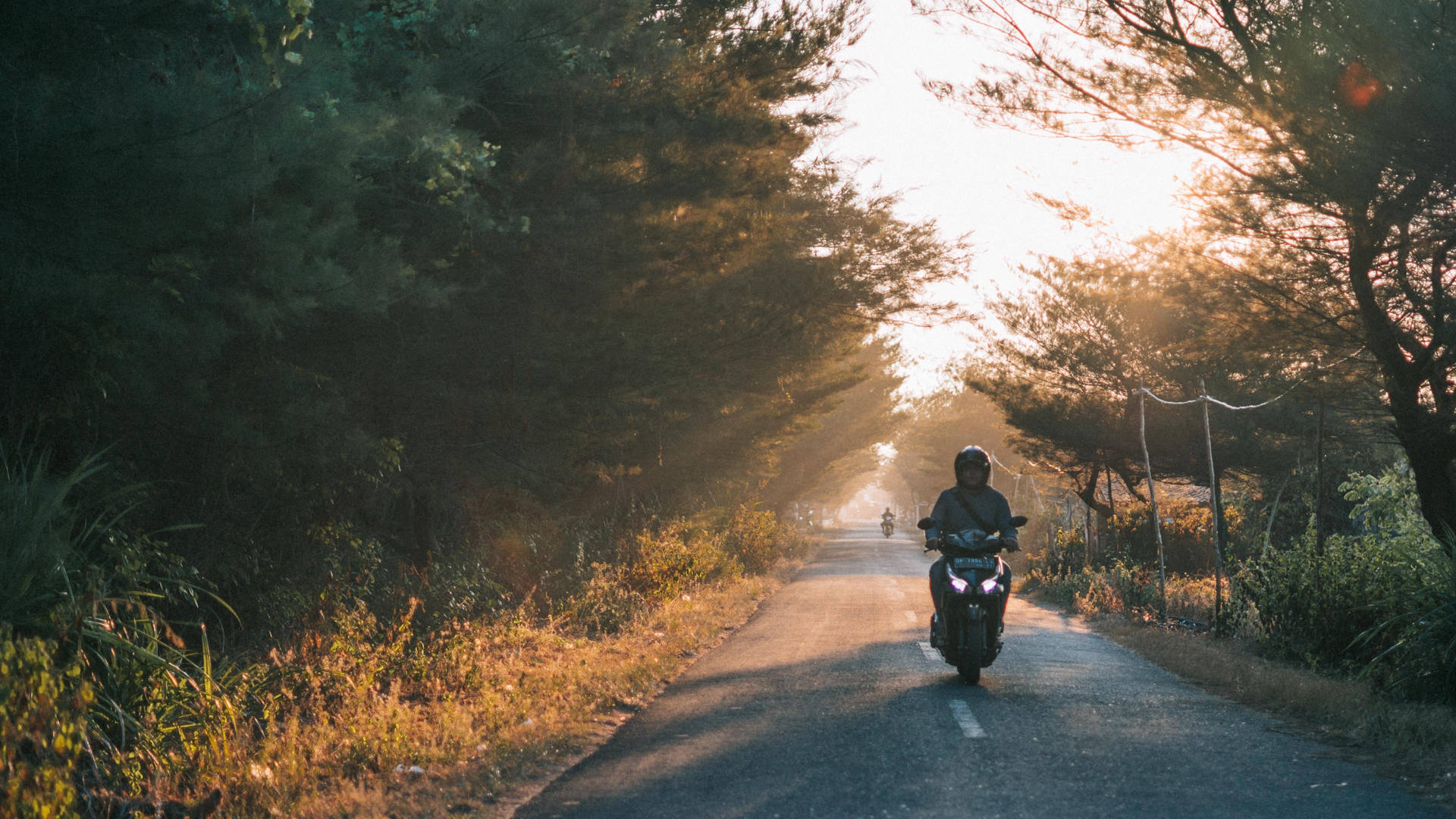 A Person Riding A Motorcycle Down A Road Background