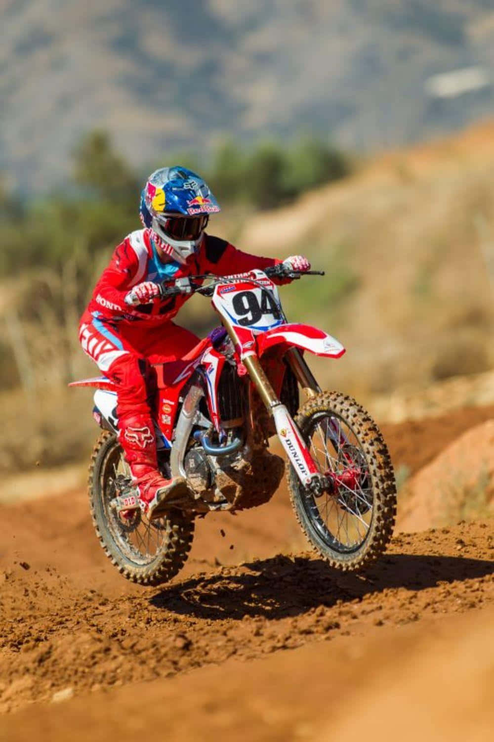 A Person Riding A Red Dirt Bike On A Dirt Track