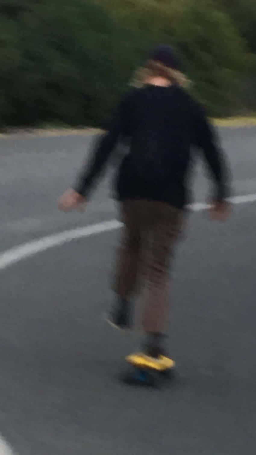 A Person Riding A Skateboard Down A Road