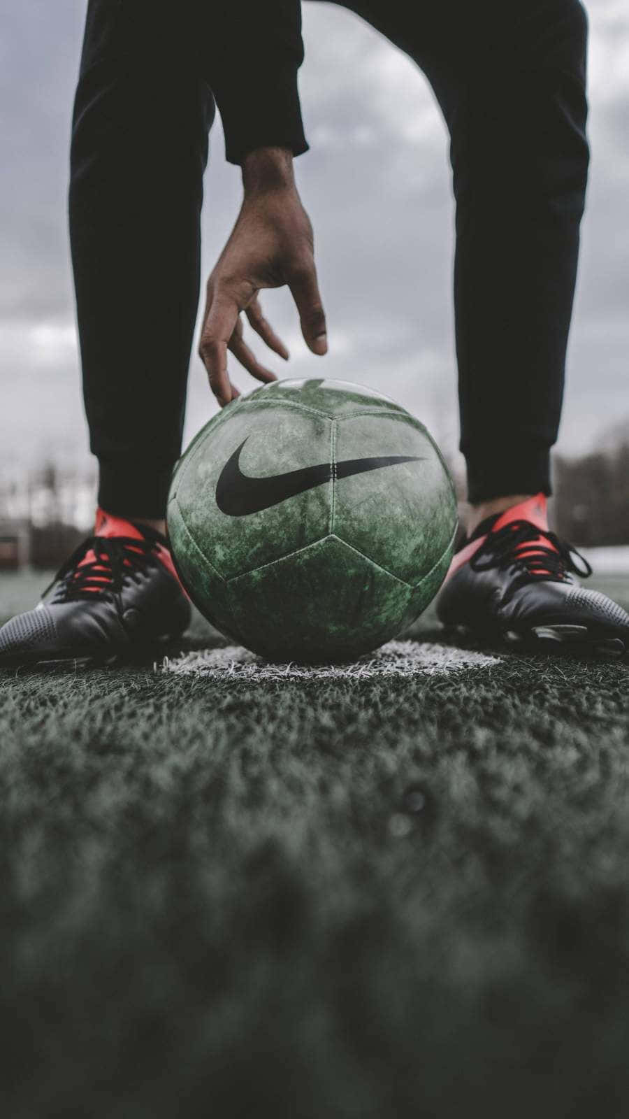 A Person's Feet Are Positioned On A Soccer Ball Background