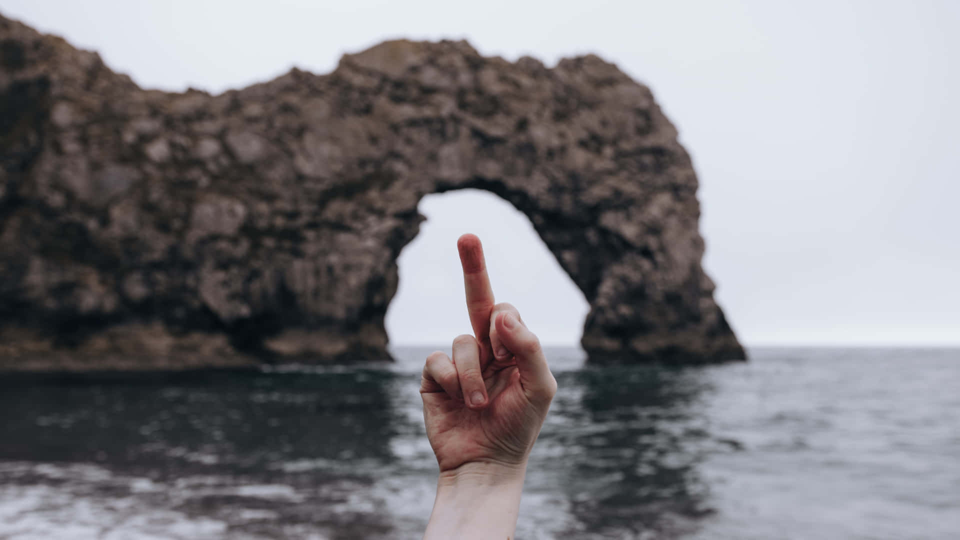 A Person's Finger Pointing At A Rock Formation