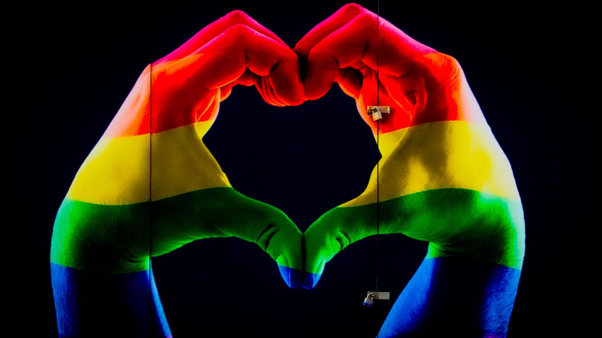 A Person's Hands Make A Heart Shape With Rainbow Colors Background