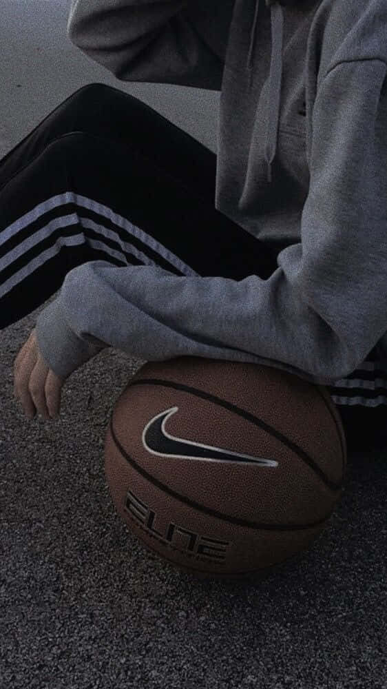 A Person Sitting On The Ground With A Basketball Ball Background