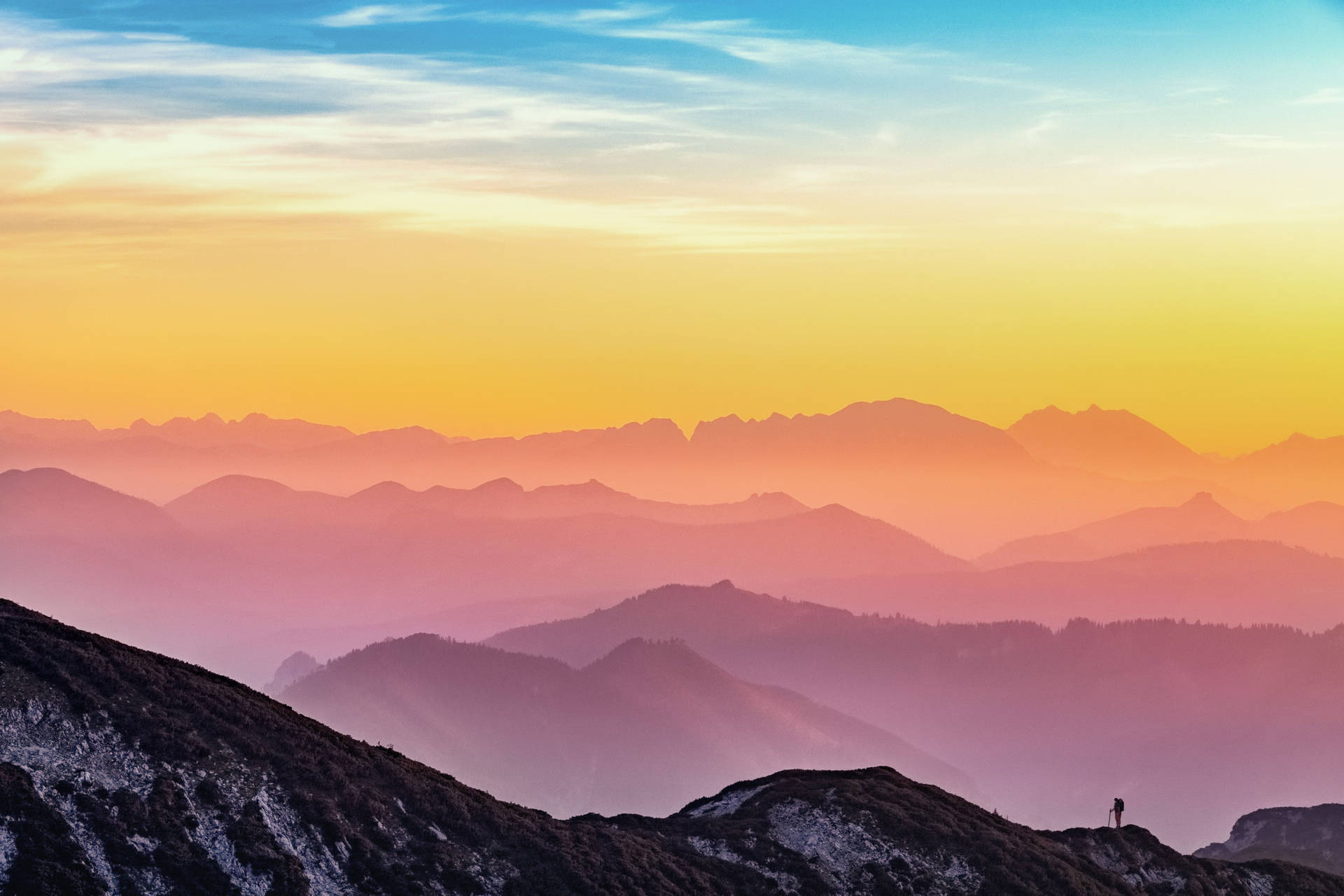 A Person Standing On Top Of A Mountain At Sunset Background