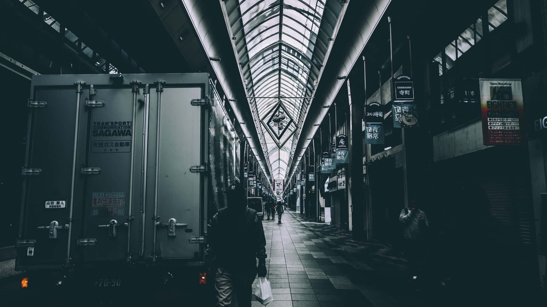 A Person Walking Down A Hallway With A Truck In The Background Background