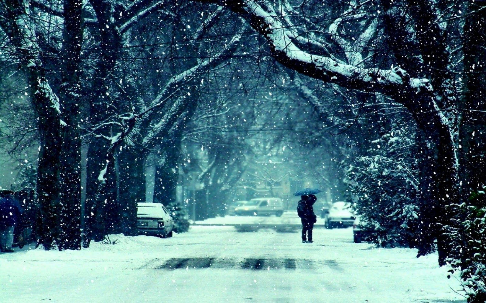 A Person Walking Down A Snow Covered Street Background