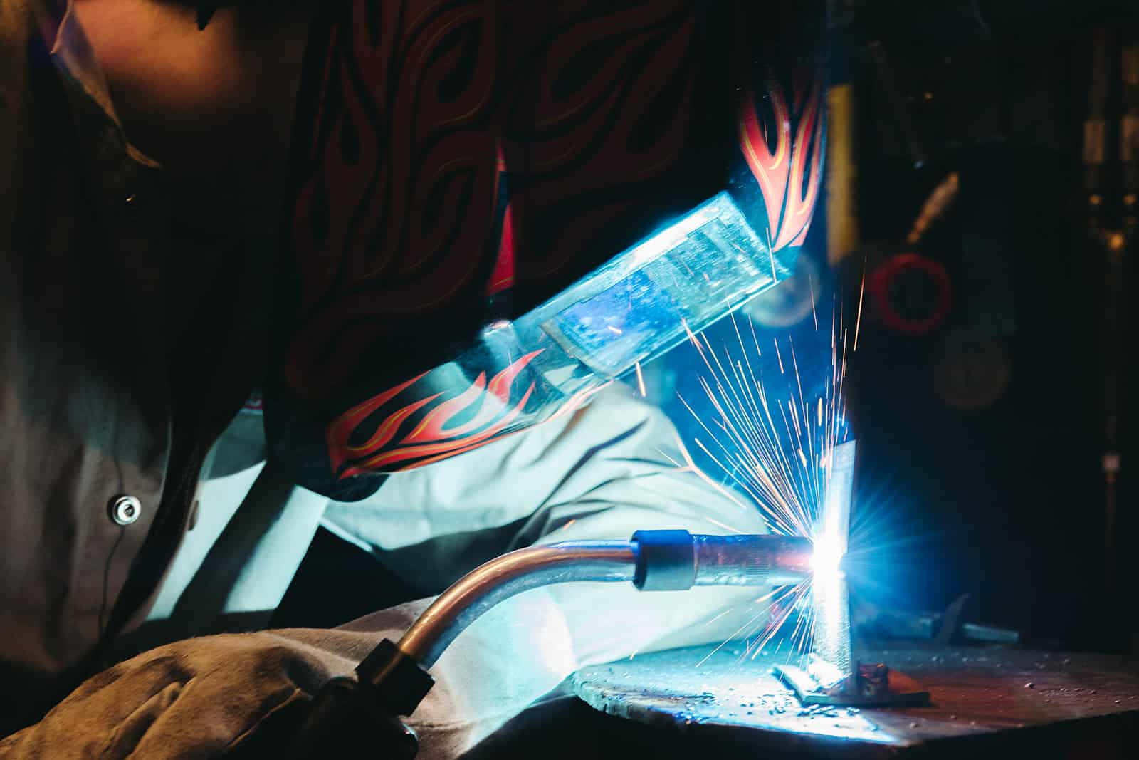 A Person Welding With A Torch Background