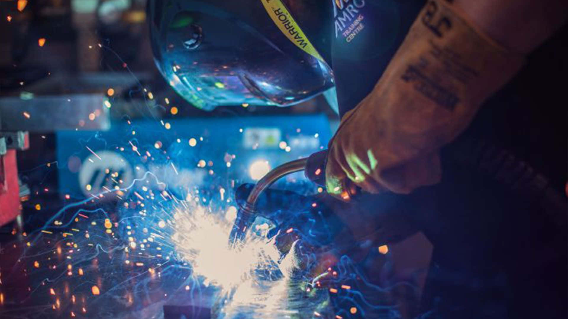 A Person Welding With Sparks In His Helmet Background