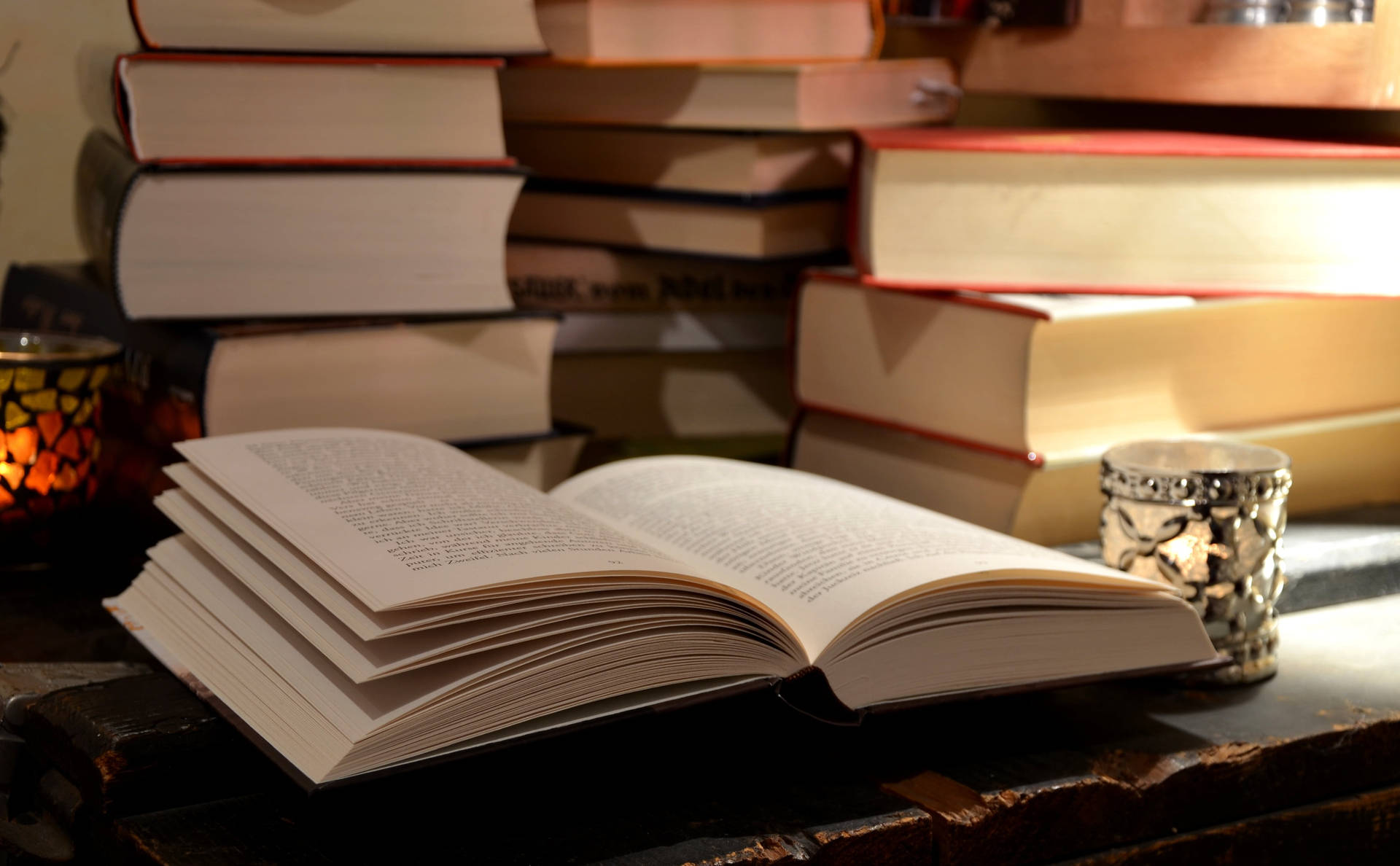 A Picture Of An Open Book On A Desk, Surrounded By Other Reference Books Background