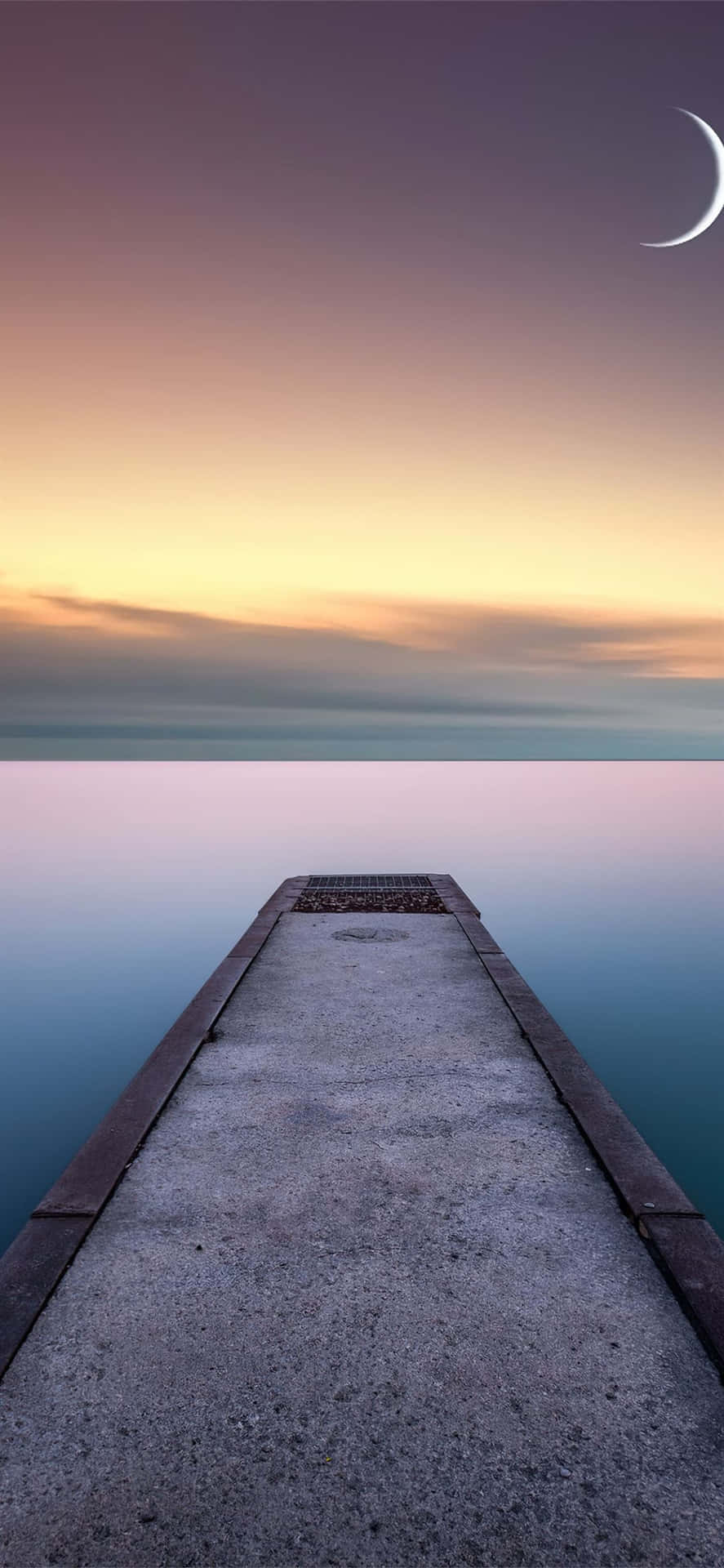 A Pier Leading To The Water With A Crescent Moon Background