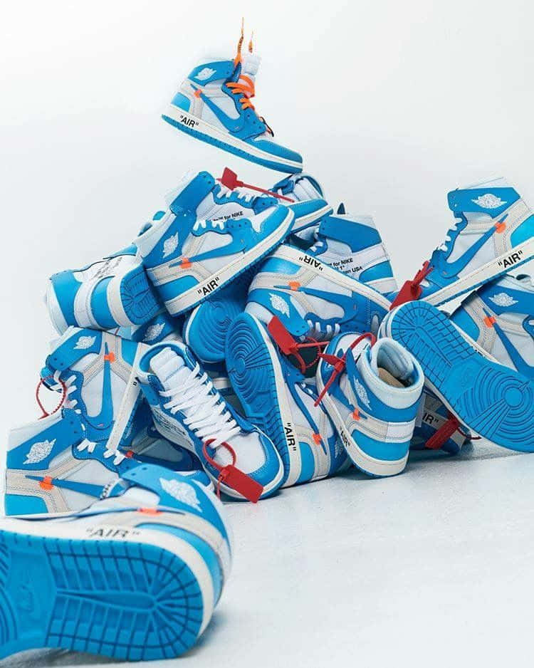 A Pile Of Blue And Orange Sneakers On A White Surface Background