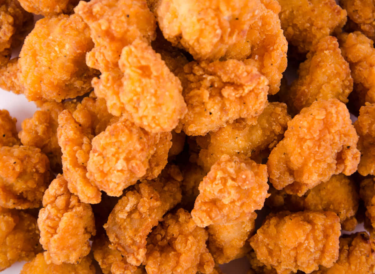 A Pile Of Fried Chicken Nuggets On A White Surface