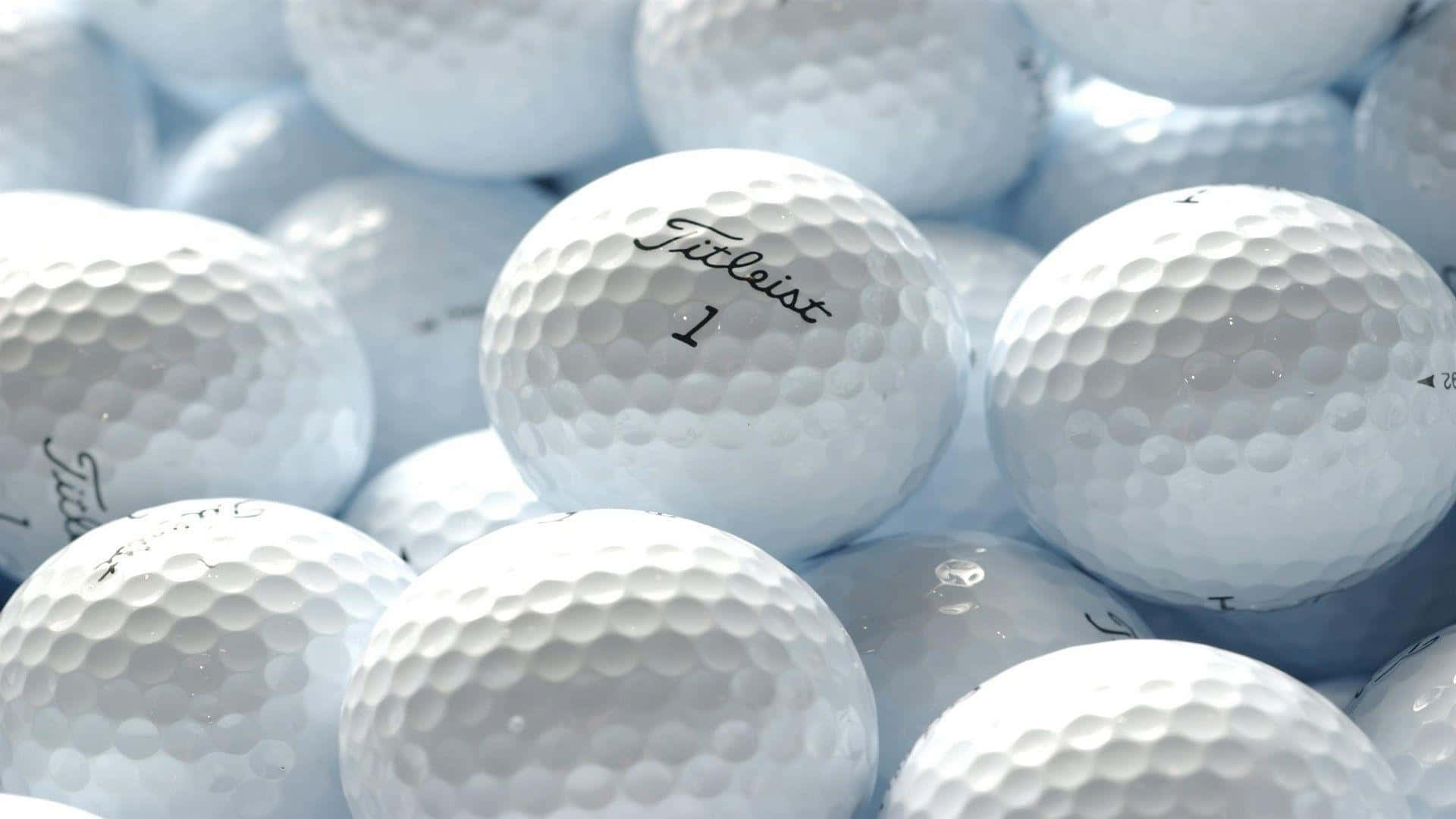 A Pile Of White Golf Balls With The Word Titleist Background