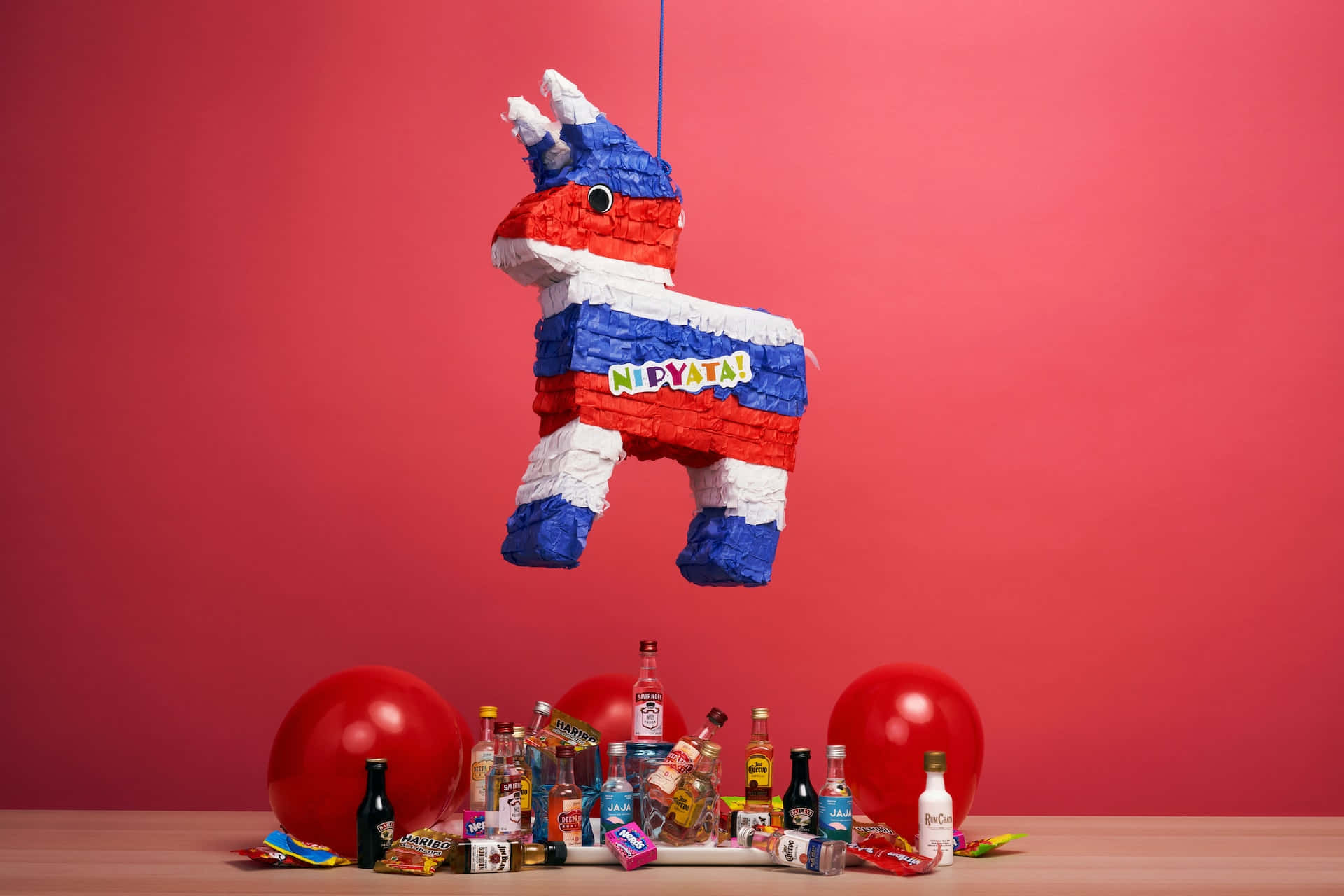 A Pinata Hanging From A Red Table With Balloons And Drinks Background