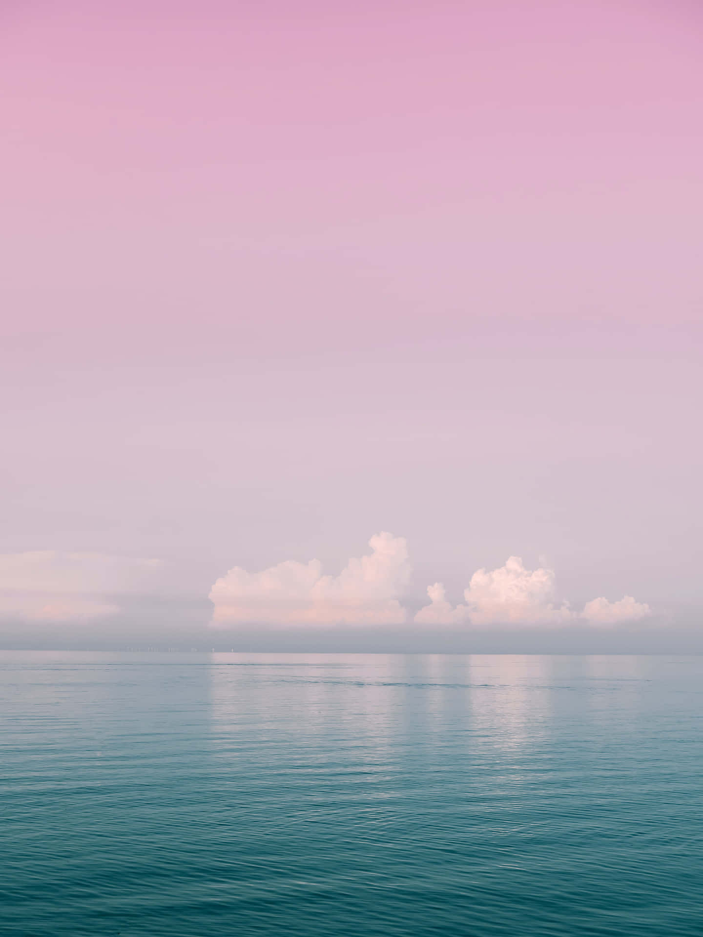 A Pink And Blue Sky With Clouds Over The Ocean Background