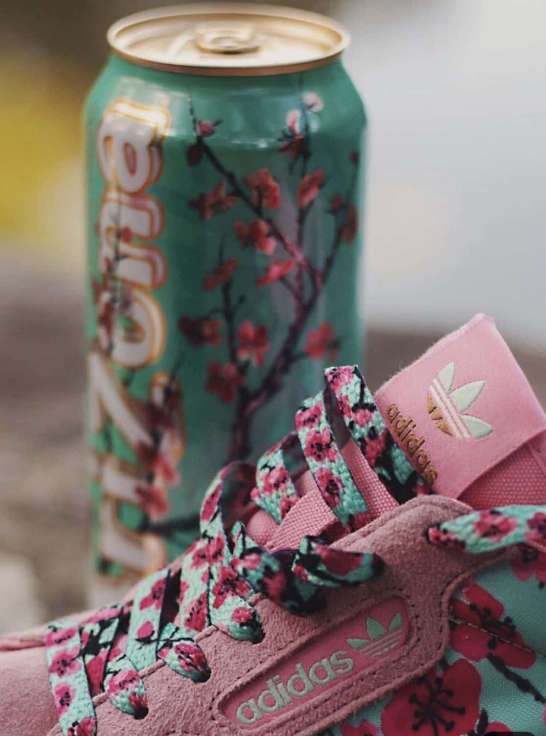A Pink And White Adidas Sneaker With A Can Of Soda Background
