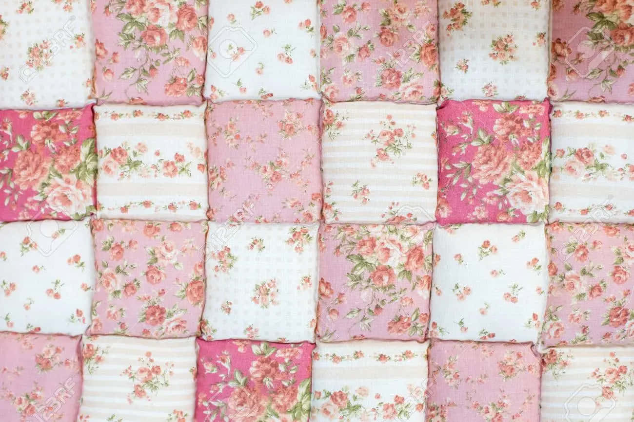 A Pink And White Quilt With Floral Patterns Background