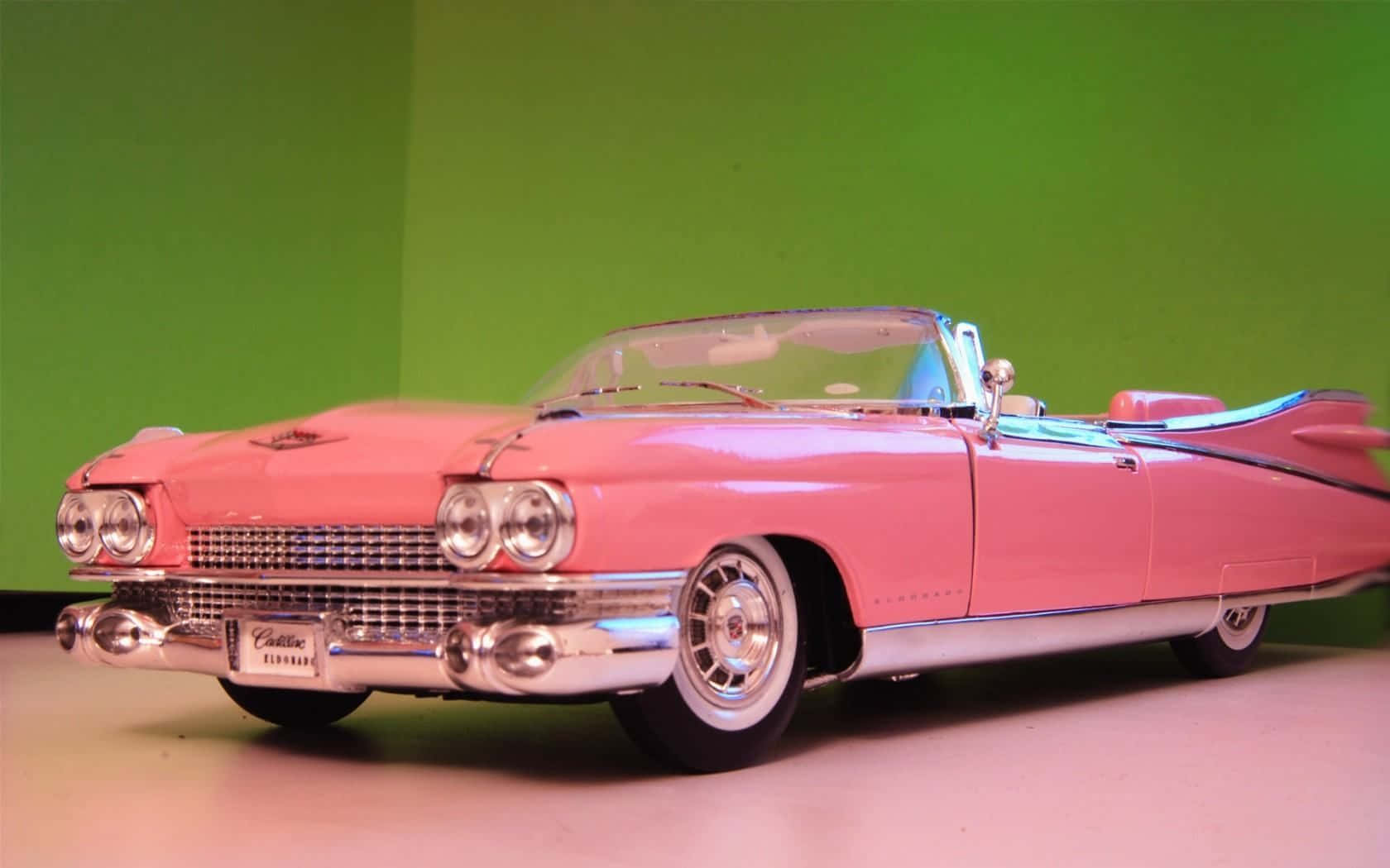 A Pink Cadillac Convertible Is On Display Background