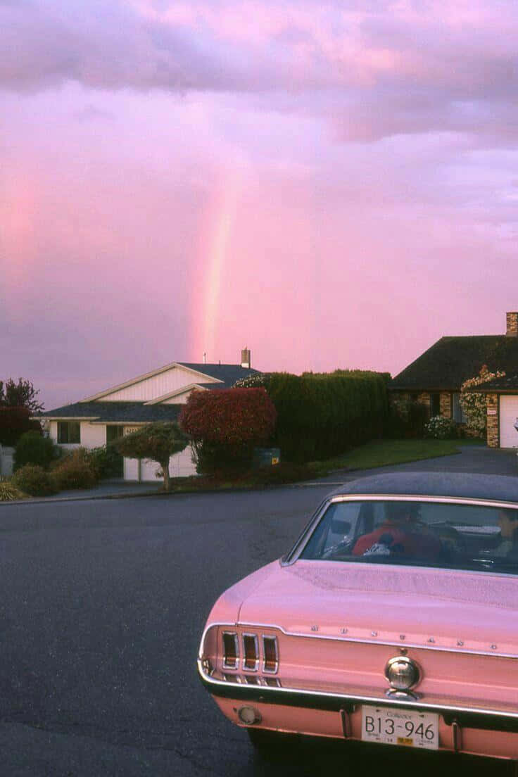 A Pink Car Parked In A Driveway Background