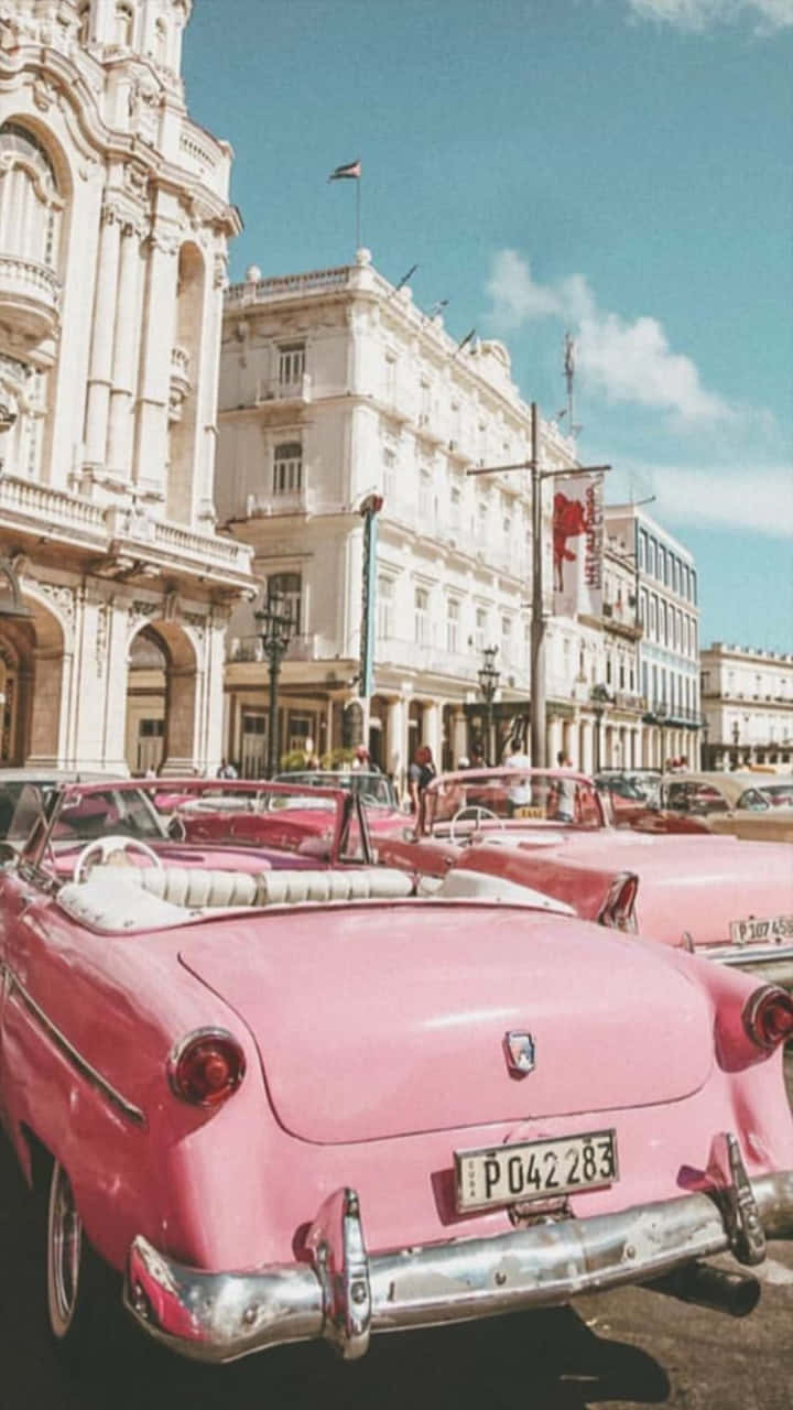 A Pink Car Parked In Front Of A Building Background