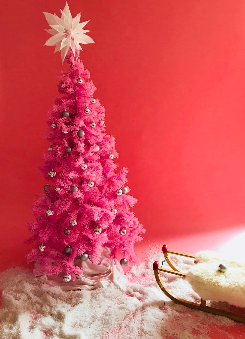 A Pink Christmas Tree With A Sled And Silver Ornaments Background