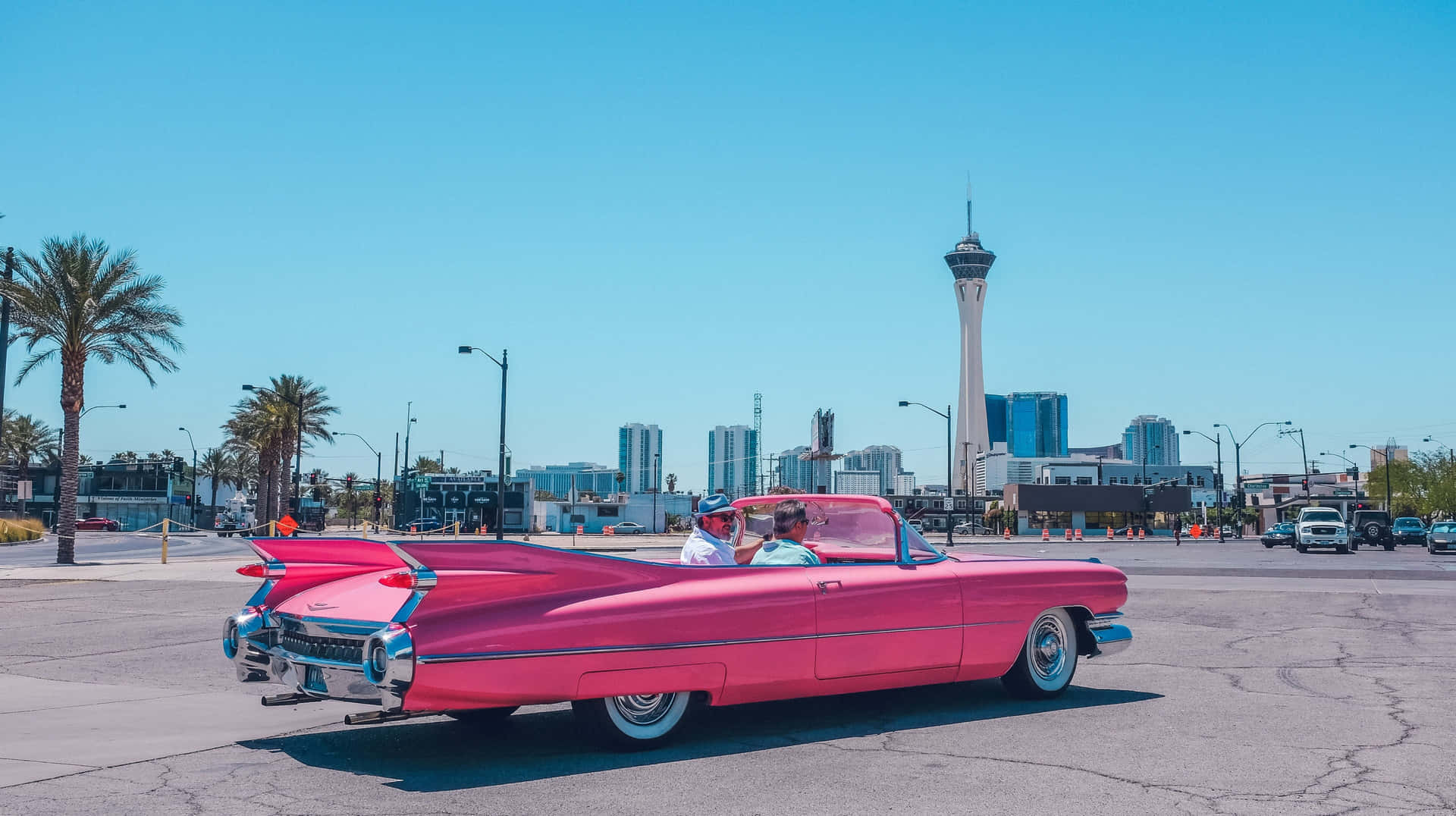 A Pink Convertible Car In The Middle Of A City Background