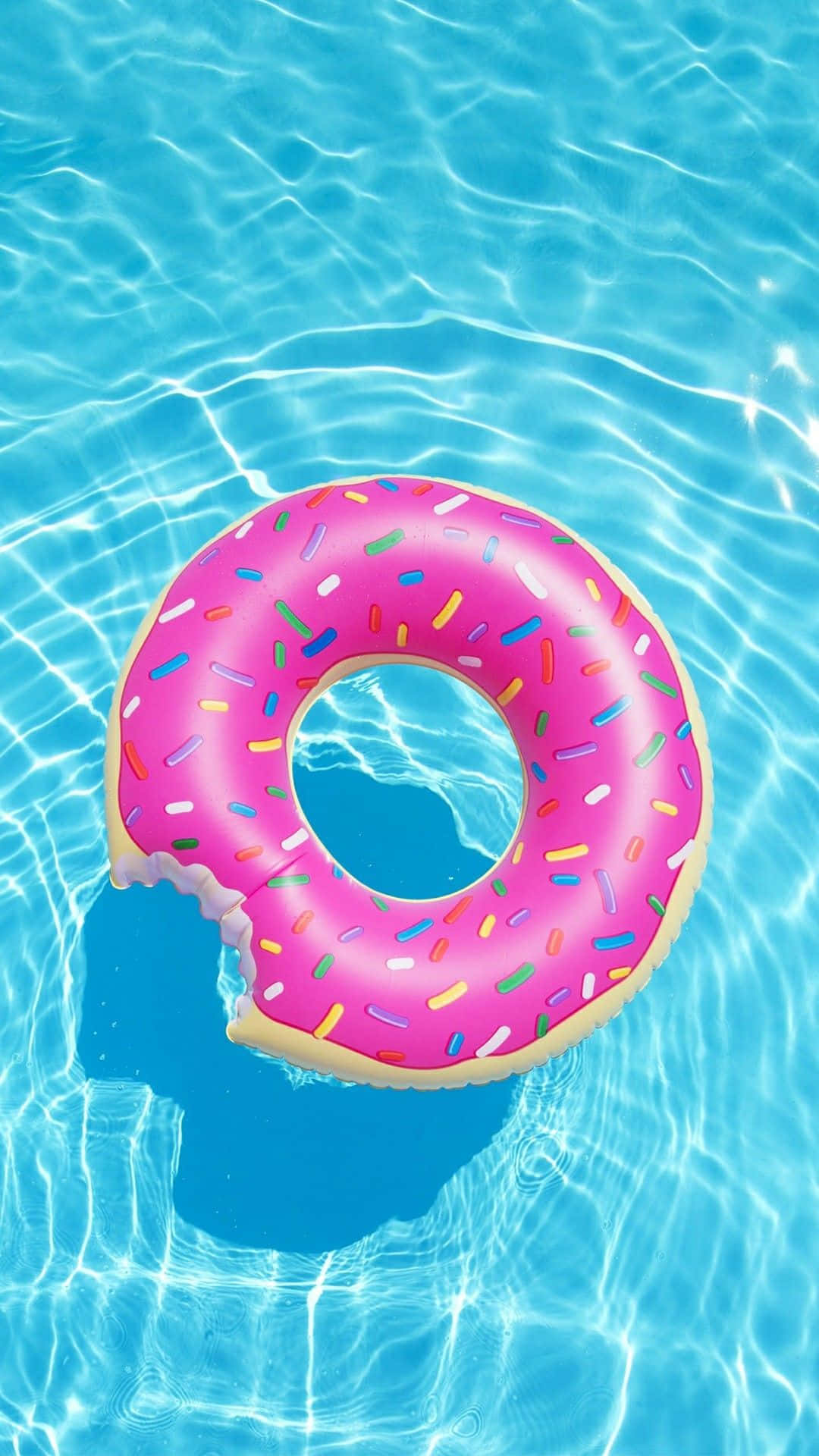 A Pink Donut Floating In The Pool Background