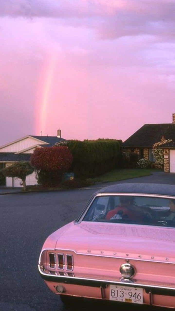 A Pink Mustang Parked In Front Of A House Background