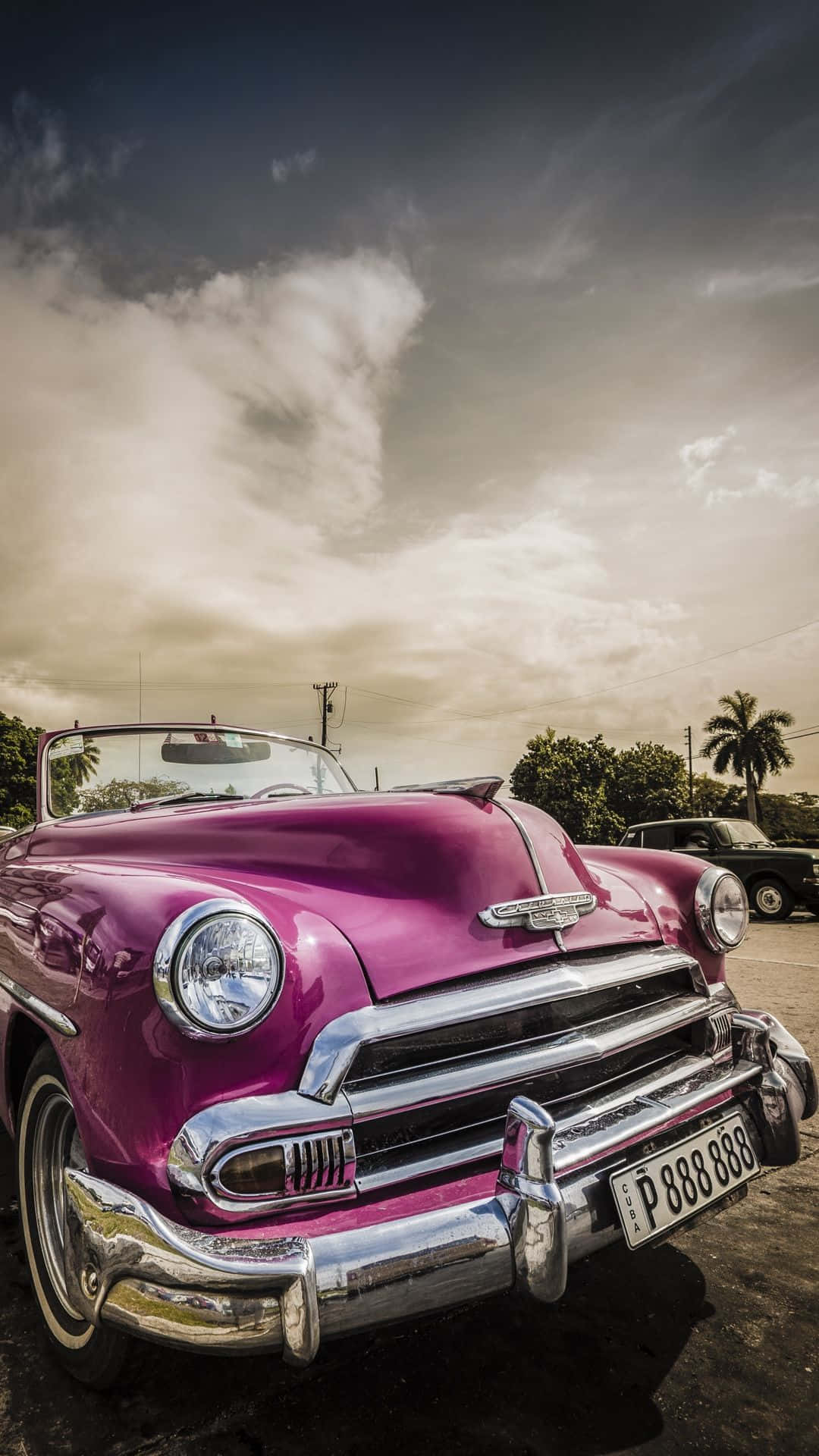 A Pink Vintage Car Parked In A Parking Lot Background