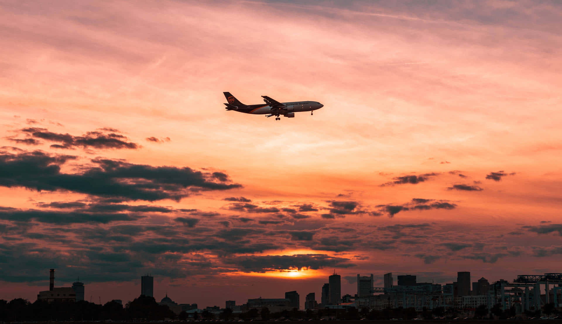 A Plane Flying Over A City At Sunset Background