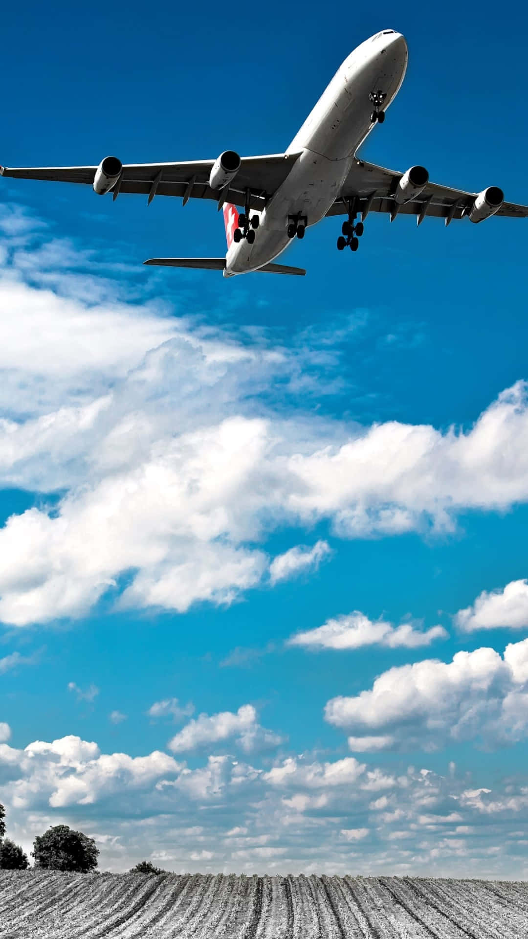 A Plane Flying Over A Field Background