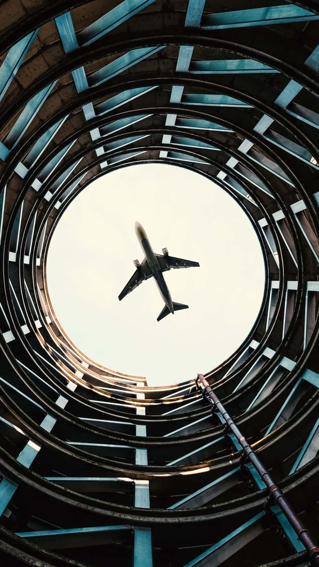A Plane Flying Through A Circular Building Background