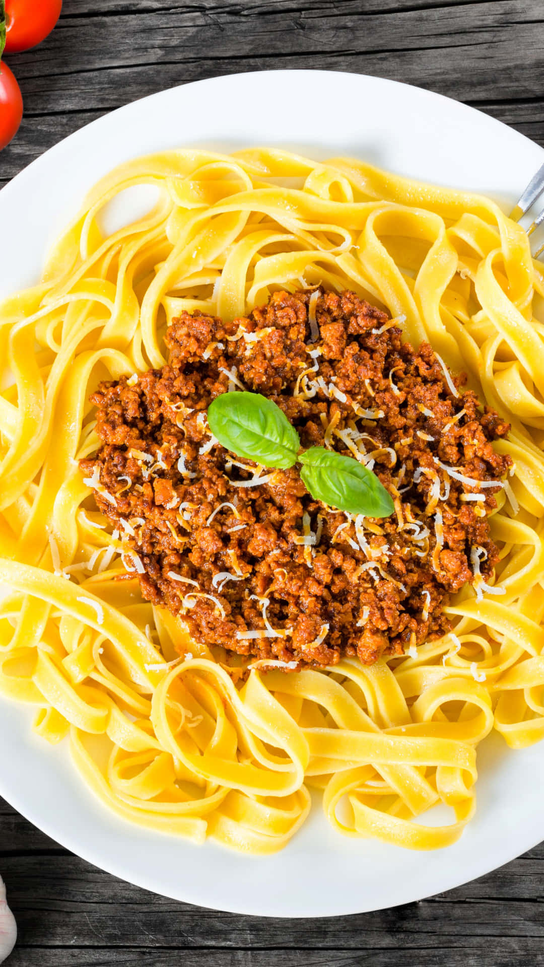 A Plate Of Pasta With Meat Sauce And Tomatoes Background