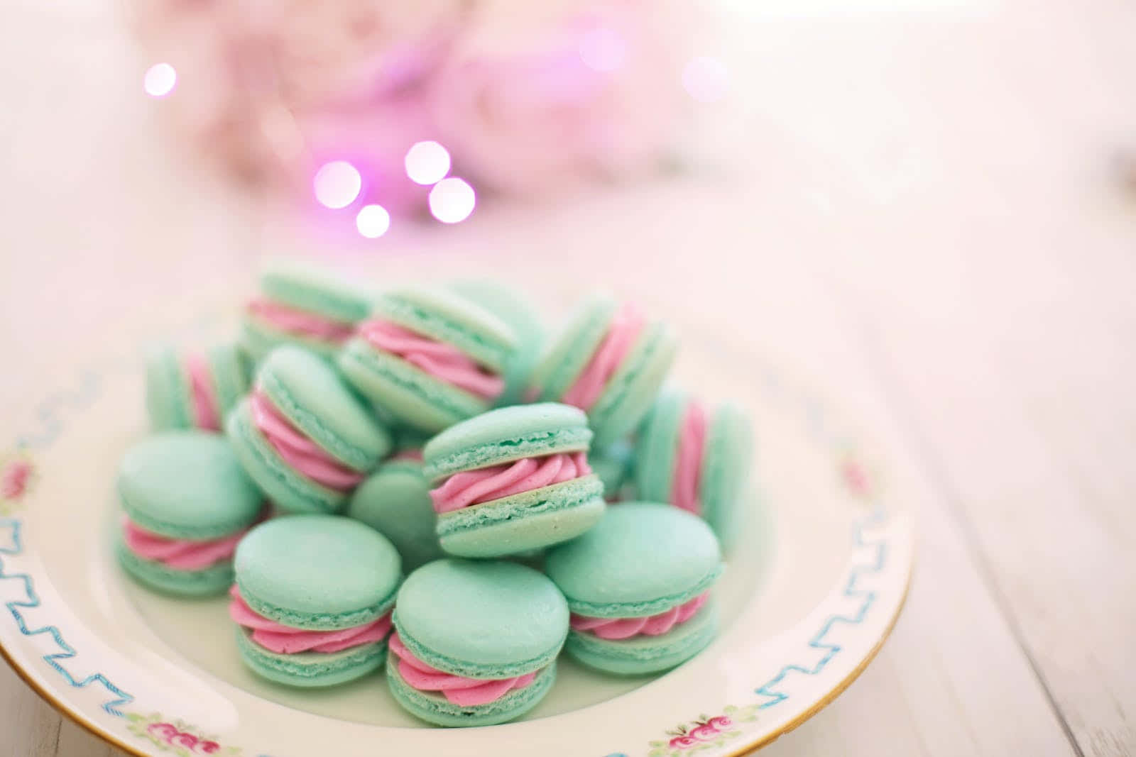 A Plate Of Pink And Green Macarons On A Table