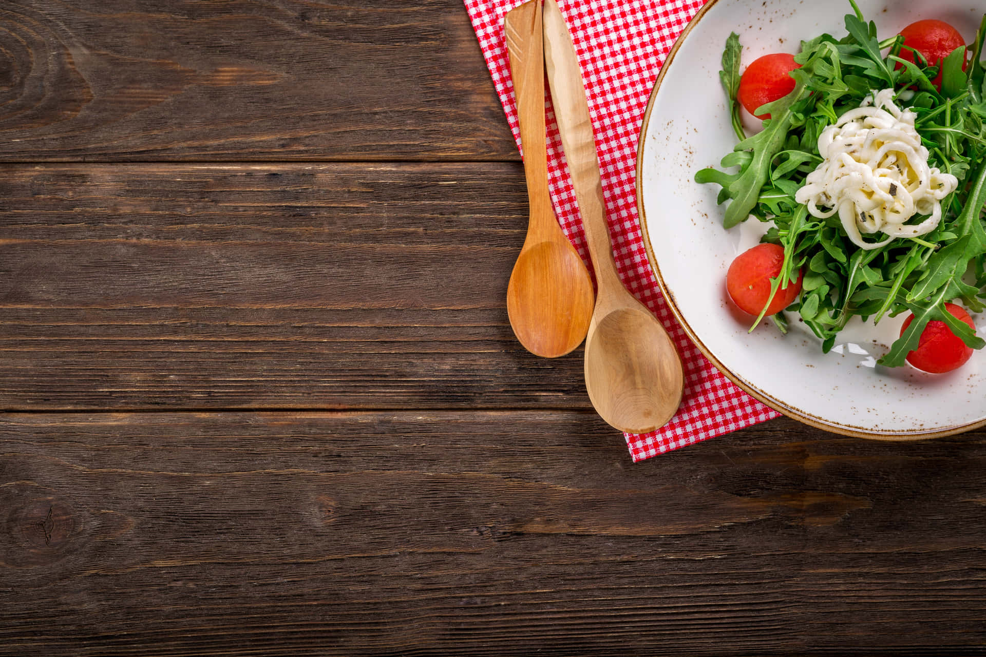 A Plate Of Salad With Tomatoes And A Wooden Spoon Background