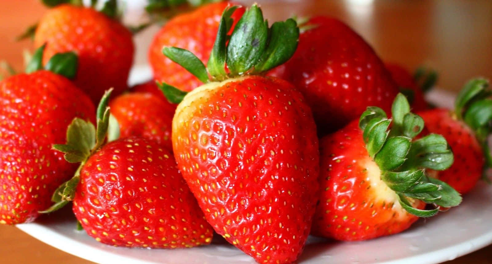 A Plate Of Strawberries On A Table Background