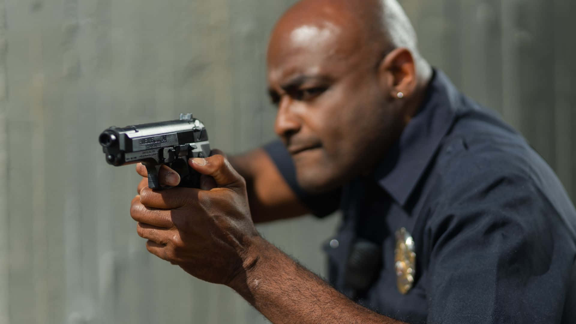 A Police Officer Aiming His Gun At A Wall